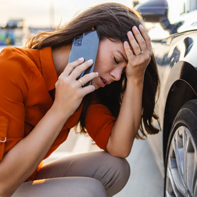 Sad woman sits at the punctured wheel of a car. Tire service and car service on call. Courses for drivers and car mechanics. Pump for car wheels. Solar glare Emergency call out